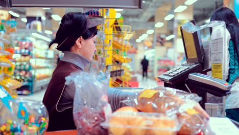 woman at the cash desk, putting merchandise on conveyor belt