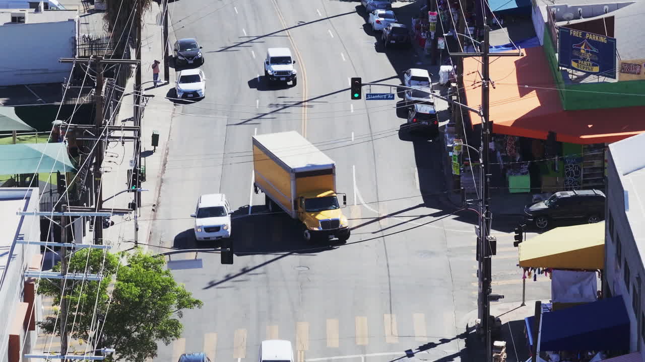 High-angle view of a busy city street with cars, pedestrians, and buildings