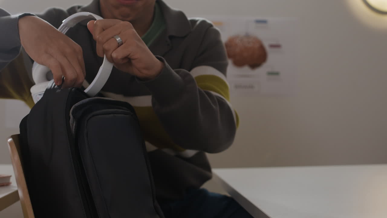 A person putting headphones into a backpack