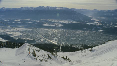 view of innsbruck from nordkette ski resort, with chairlift and skiers