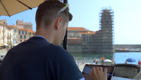 Young-male-entrepreneur-working-on-his-iPad-in-Collioure,-France