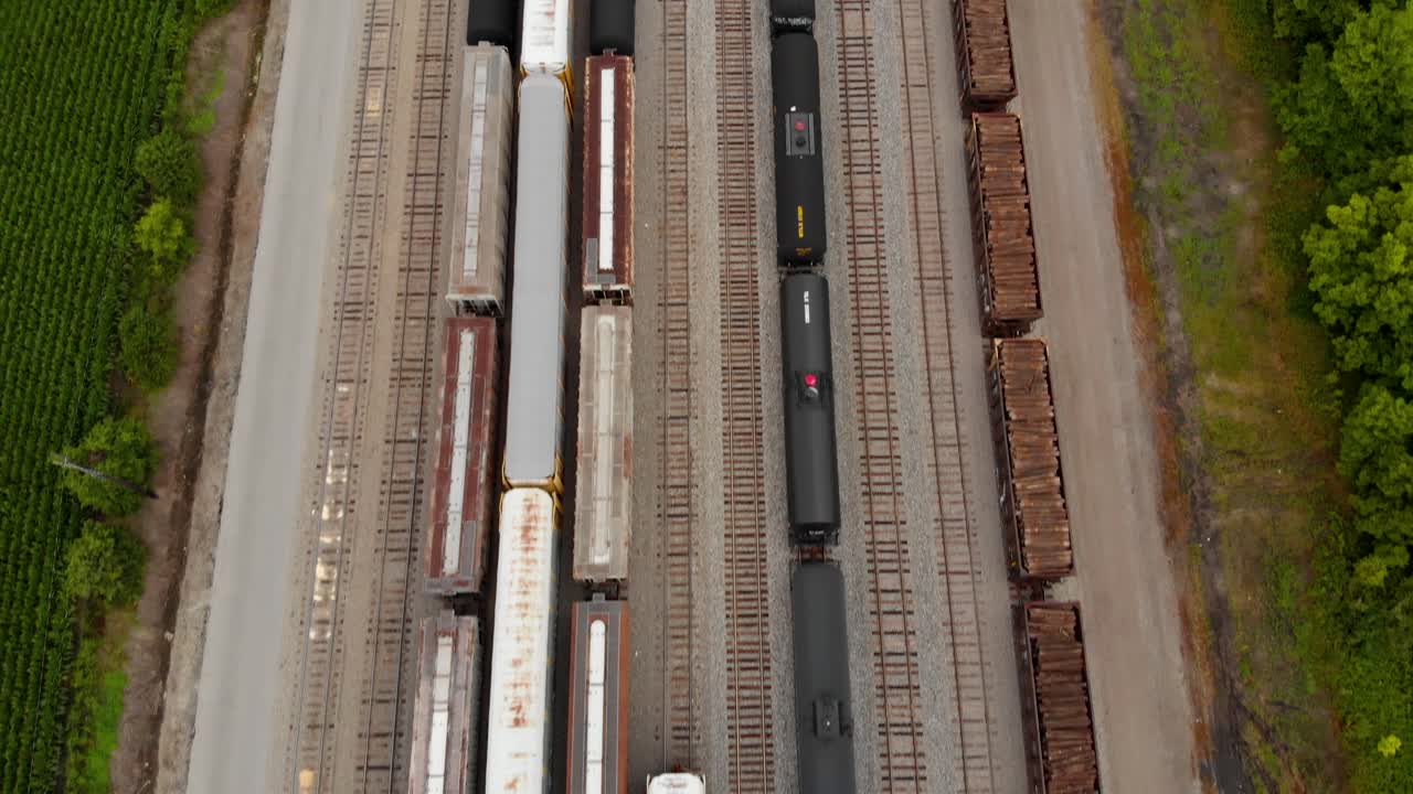 vista aerea 4k di più treni seduti in una stazione ferroviaria mentre si rivela una lunga ferrovia diritta con più binari avanti accanto a una piccola città