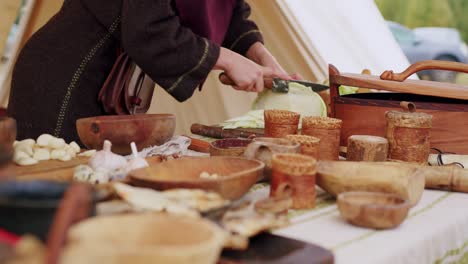 Close-up-of-a-woman-in-medieval-costume-cutting-the-cabbage-to-prepare-historical-dish-like-centuries-before