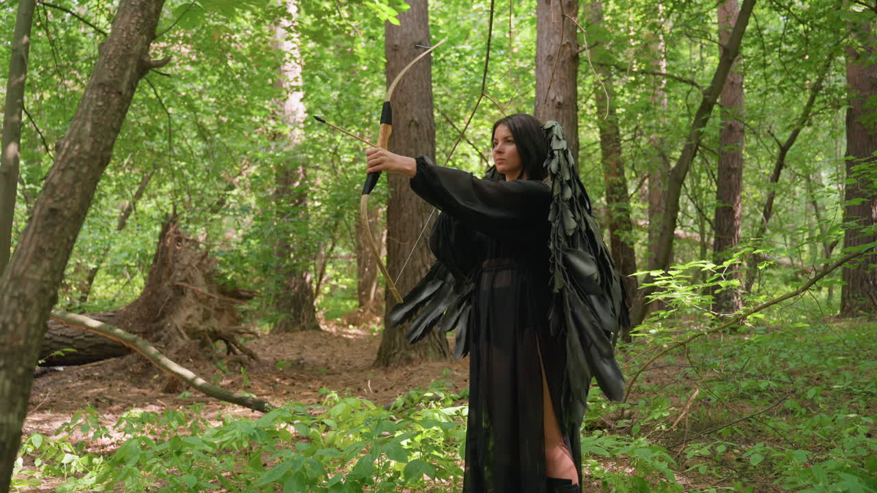 Black fairy with dark wings stands in green forest aiming arrow at unseen attacker, sunlight flickering through leaves, capturing tension, focus, and mystical power in natural setting