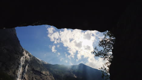 vista a través del arco en las rocas a las altas montañas con una cascada en la parte superior cerca del briksd