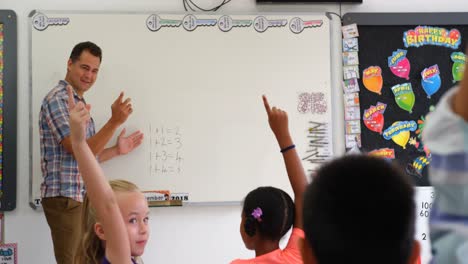 side view of caucasian male teacher teaching schoolkids on whiteboard in the classroom 4k