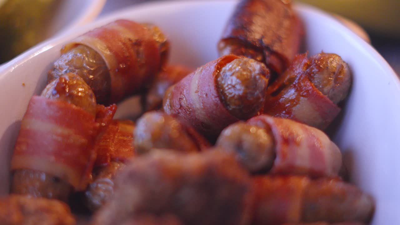 deliciosos cerdos en mantas carne de cerdo salchicha en el plato de servicio en la mesa de la cena. comida británica tradicionalmente servida en navidad 4k.