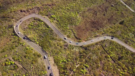 cars driving on curvy mountain road in tenerife island, aerial top down view