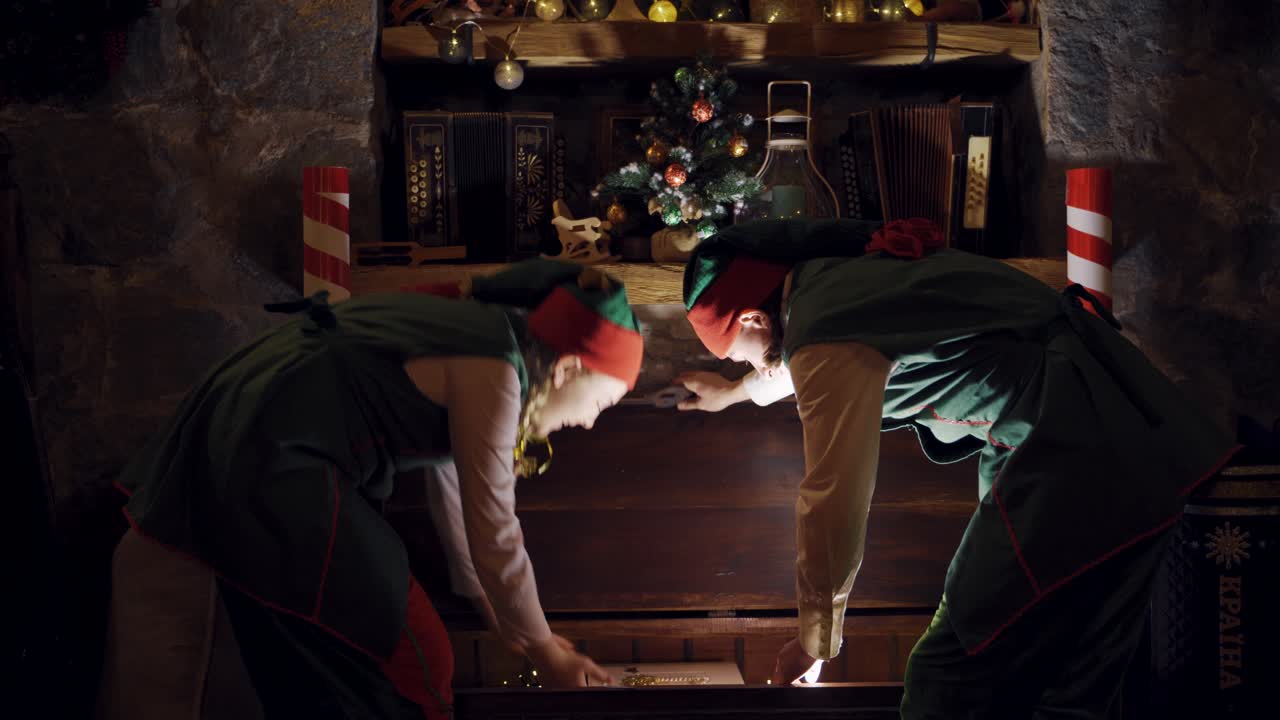 Elves taking magic book out of the big chest. Dark background of the room at Christmas time and fairy elves opening the large box.