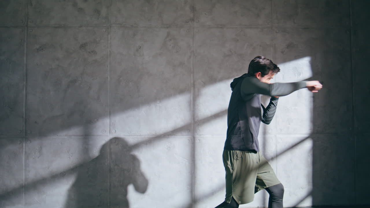 Angry fighter practicing kicks at speed intensity training. Man fighting at gym