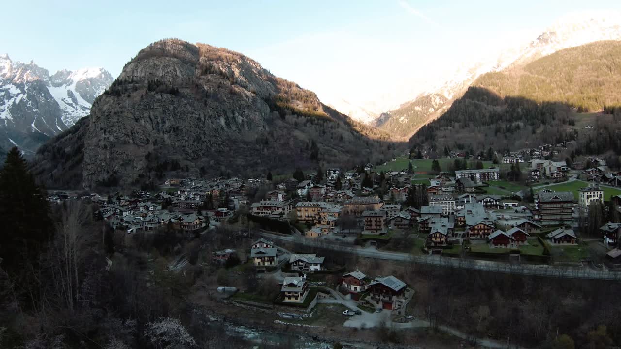 Ripresa aerea con drone FPV nella località alpina di Courmayeur, Valle d'Aosta, Italia, ai piedi delle Alpi (Monte Bianco), che vola sopra case e alberi