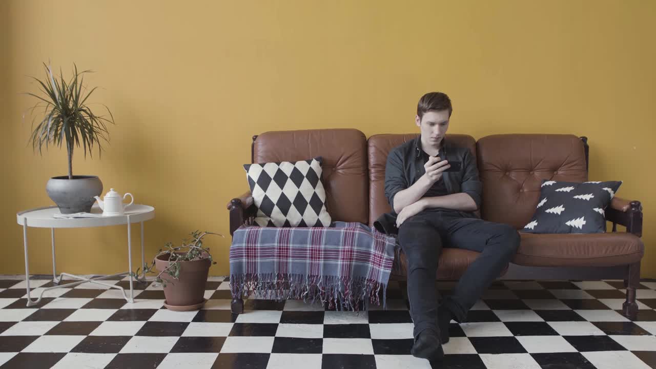 hombre usando el teléfono en un sofá en una sala de estar