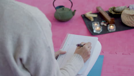 Mujer-Sentada-En-El-Suelo,-Escribiendo-Notas-En-El-Diario-Durante-La-Meditación.