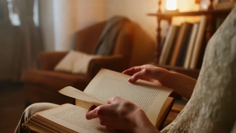 hands turning pages of a book in a cozy home setting