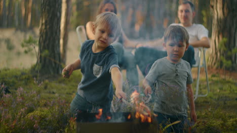 two boys sitting by a fire against a tent in the woods on the shore of the lake fry marshmallows on fire. brothers 3-6 years together burn sticks on fire