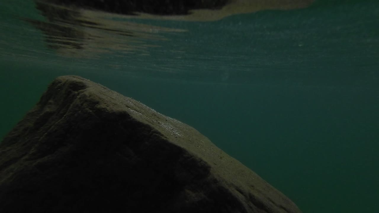 la nieve está cayendo en el lago con agua turquesa cristalina rodeada de bosque