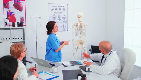 assistent pointing on skeleton in front of medical stuff