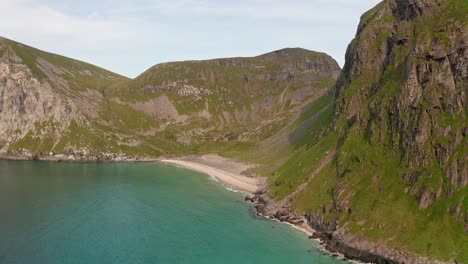 Aerial-shot-of-remote-Lofoten-Sandvika-beach-in-Noway-surrounded-by-steep-cliffs