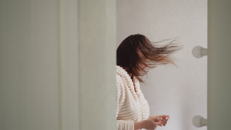 mujer se mueve a la música en el reflejo del espejo en el inodoro. joven mujer morena con el cabello mojado se divierte con la música después de tomar la ducha en cámara lenta