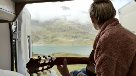 young woman in his van playing guitar