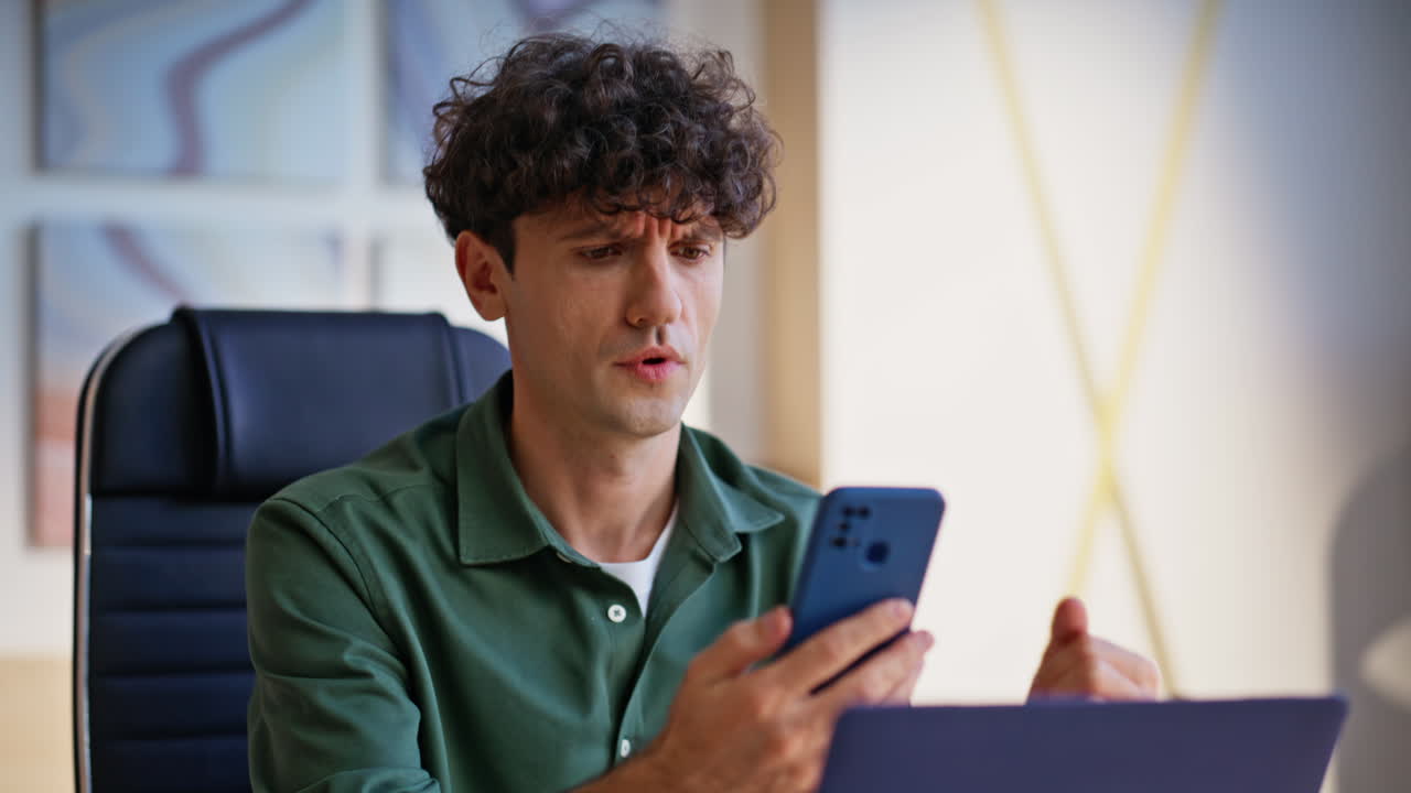 Frustrated Man Using Smartphone in Office