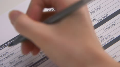 a caucasian woman's hand fills out a rental application