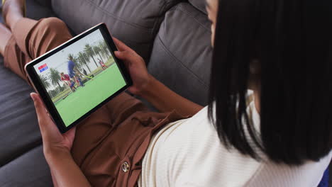 composite of woman sitting at home on couch watching hockey match on tablet