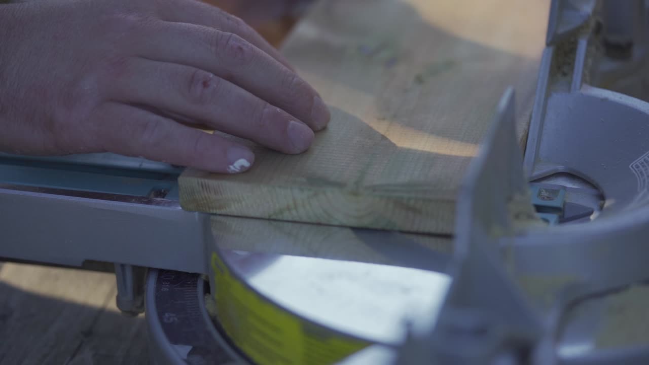 cámara lenta, hombre preparándose para aserrar tablón de madera con sierra de inglete en taller