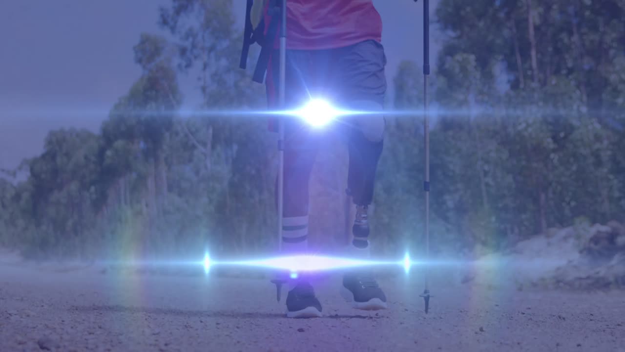 video de luces sobre hombre biracial con pierna protésica y muletas caminando en la naturaleza
