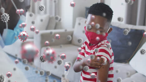 animation of covid 19 cells over african american boy in face mask receiving vaccination