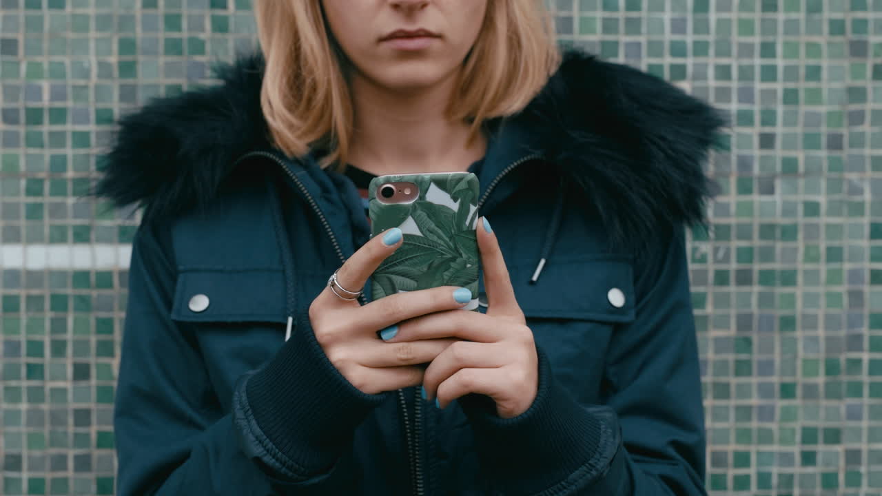 молодая женщина, использующая смартфон, отправляет текстовые сообщения в социальных сетях, ожидая в городе