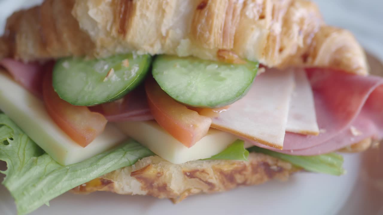 sándwich de croissant con jamón, queso, lechuga, pepino y tomate