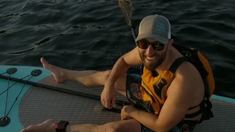 happy man paddle boarder thumbs up slomo sunset closeup