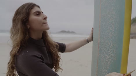 woman preparing surfboard on the beach