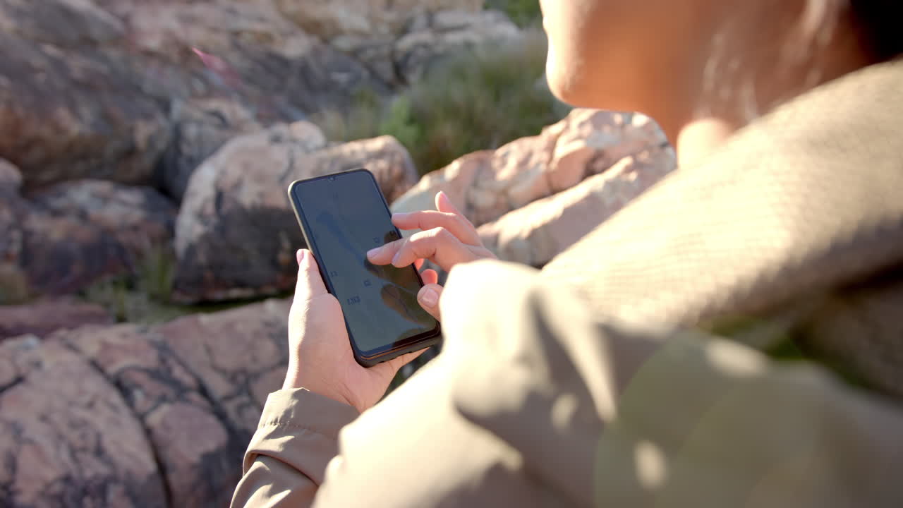 Hiking in mountains, woman using smartphone for navigation and taking photos