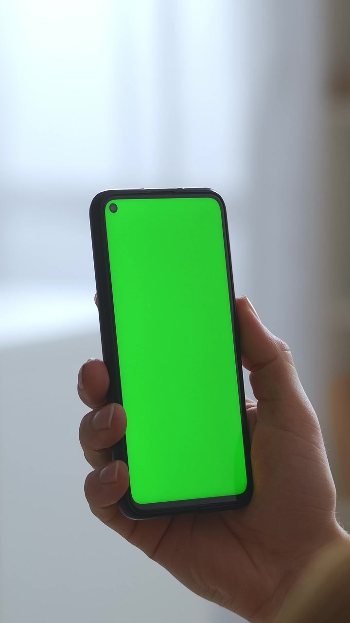Primo piano di mano che tiene uno smartphone verticale con schermo verde