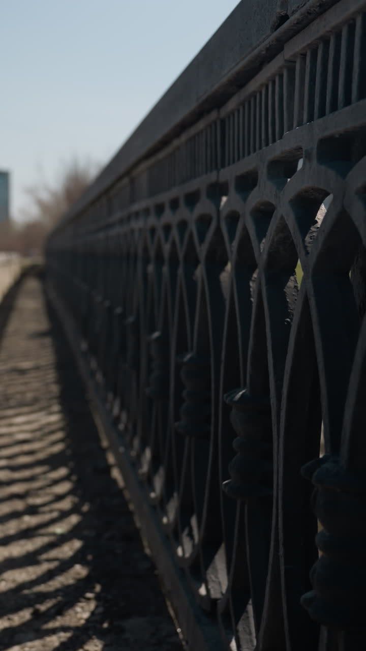 vista cercana de una carretera urbana con vehículos en movimiento en el fondo, se centra en la barrera de la carretera con sombras proyectadas por la barandilla
