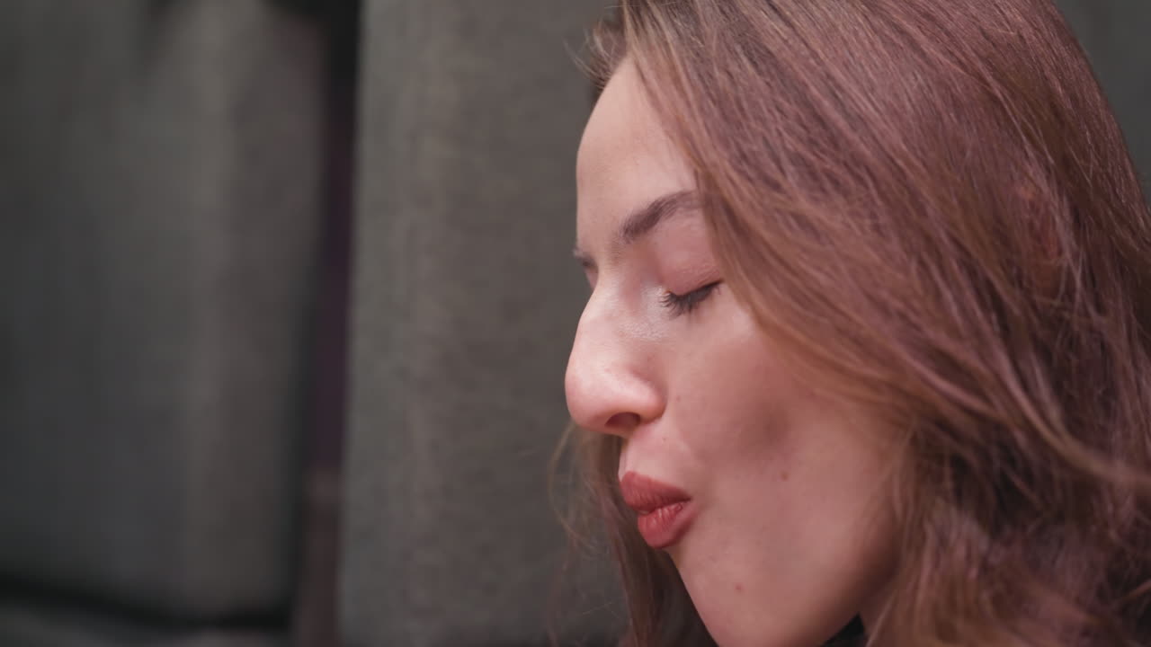 Close-up side view of lady with closed eyes enjoying bite of waffle using fork, smiling with delight. Scene captures warm moment of indulgence in relaxed setting with soft lighting and cozy background