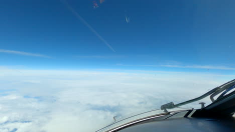 Contrail-in-blue-sky-as-airplane-flies-at-elevation-above-clouds