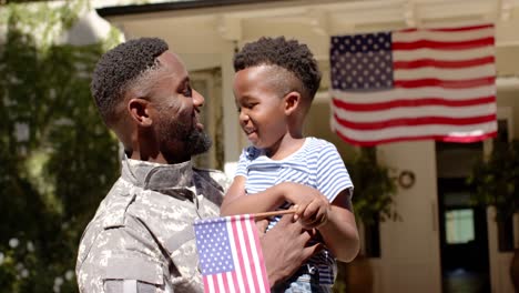 Glücklicher-Afroamerikanischer-Soldat,-Der-Seinen-Sohn-Mit-Amerikanischer-Flagge-Umarmt,-In-Zeitlupe