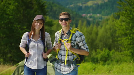 Portrait-Of-A-Couple-Of-Happy-Tourists-With-Backpacks-Smile-Look-At-The-Camera-4K-Video