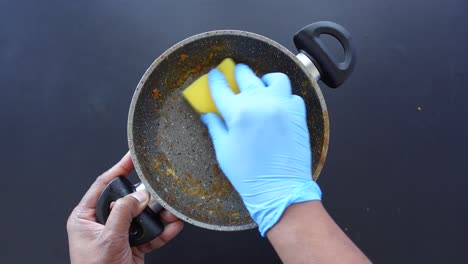 cleaning a dirty pan with a sponge