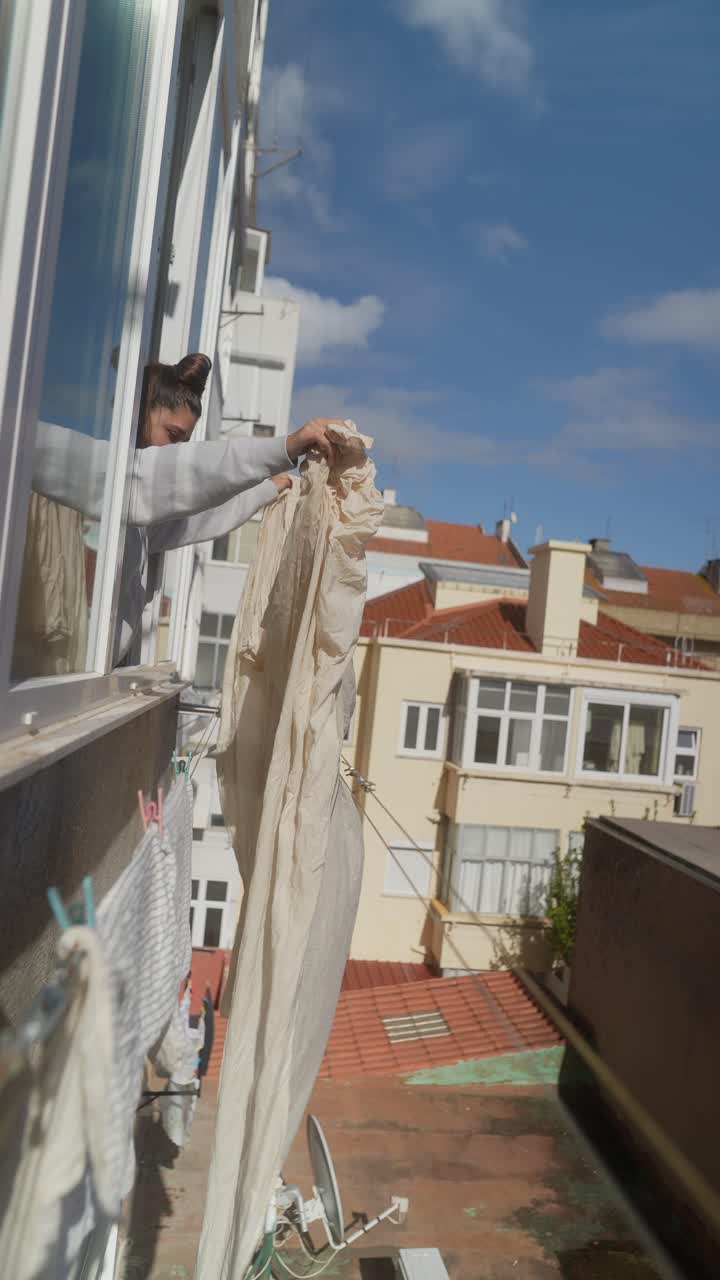 Woman Drying Clothes on an Apartment Balcony