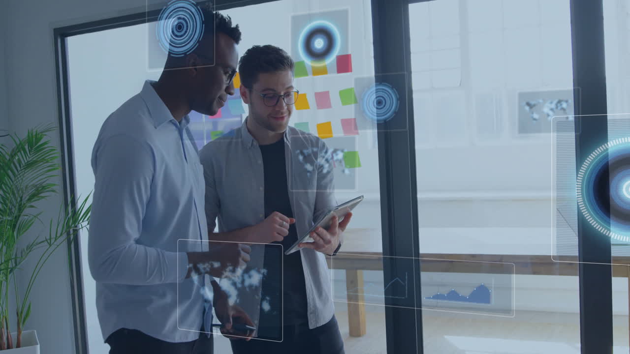 Two male coworkers collaborating over tablet in business office, displaying floating data charts