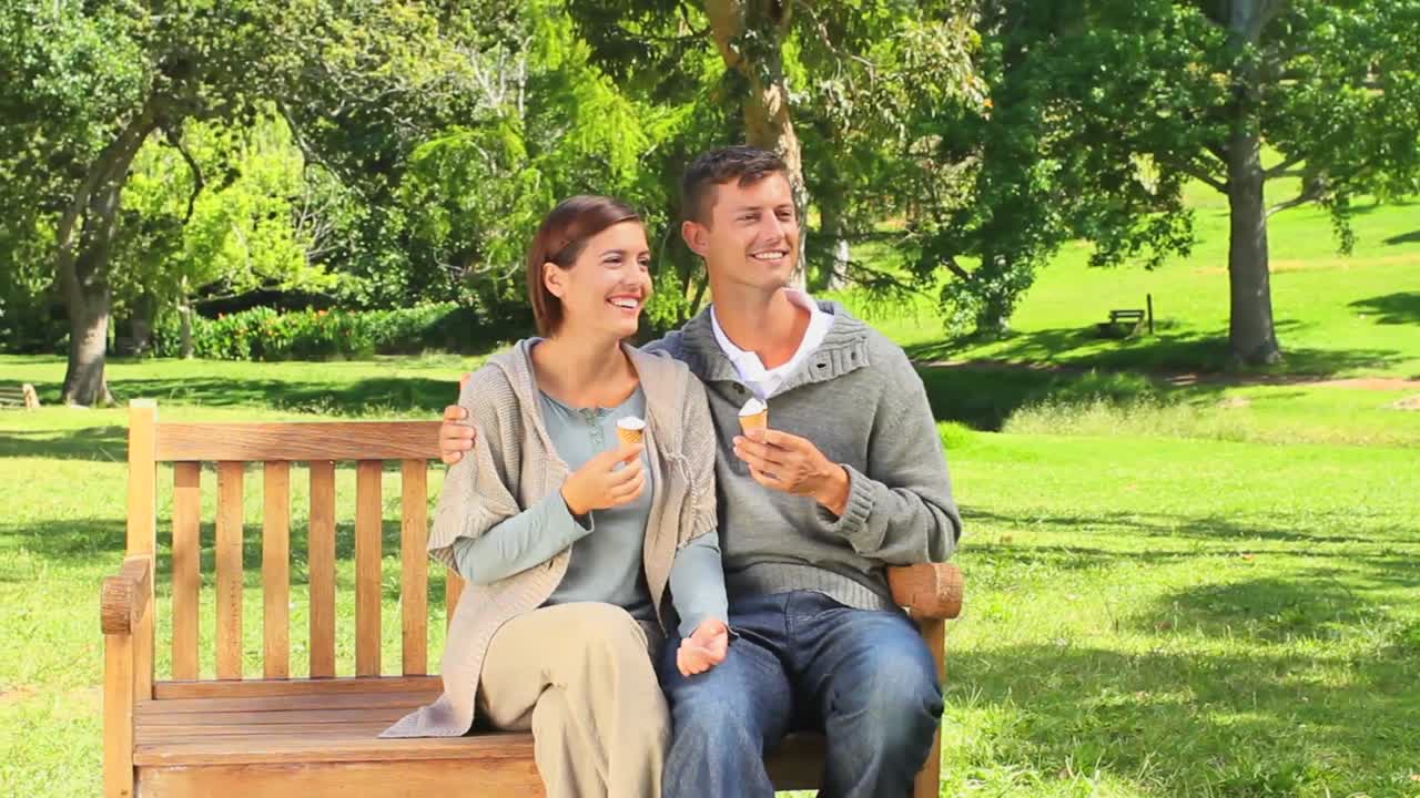 젊은 커플이 밖에서 아이스크림을 먹고 있다