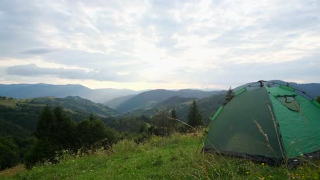 tourist tent stands on green grass on a background of mountains green tent for camping on top of the mountain with a beautiful view