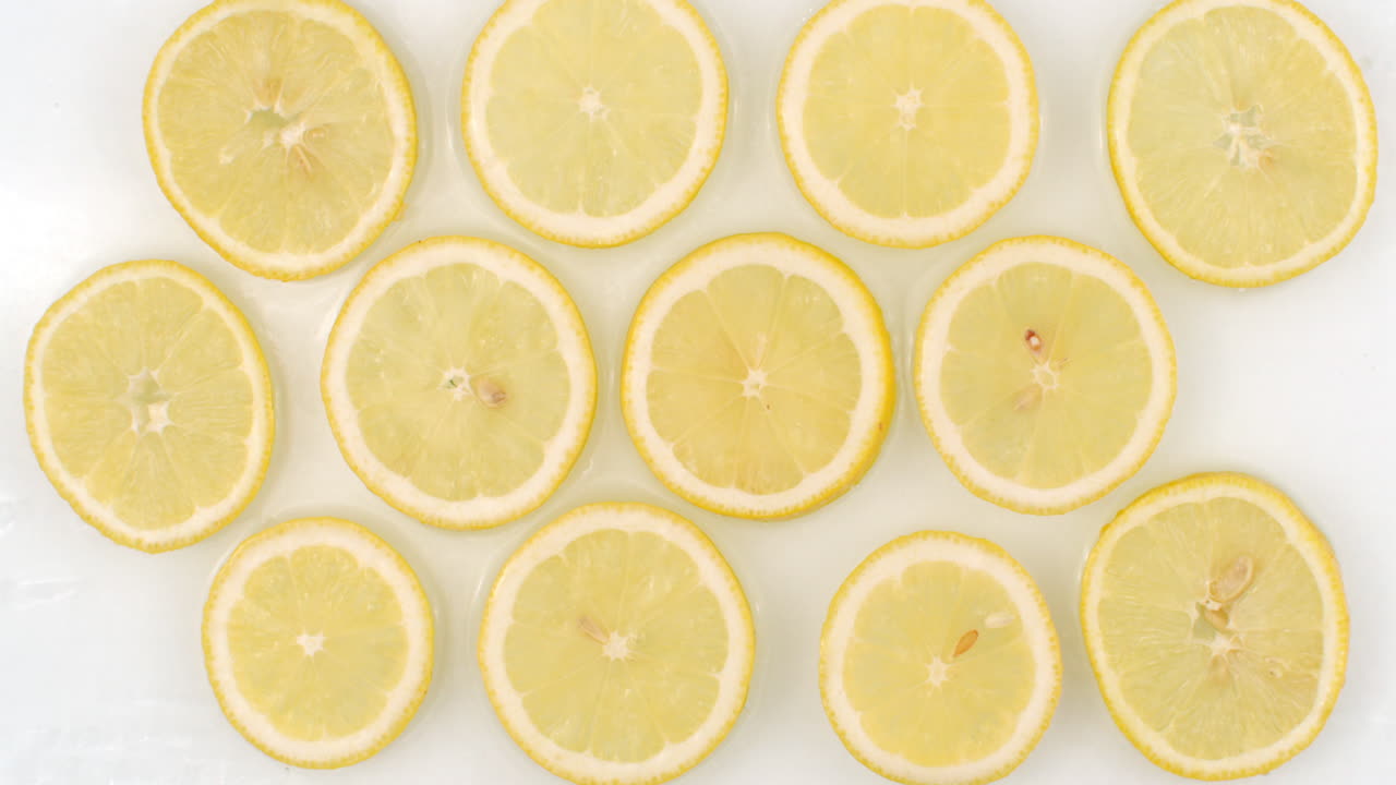 vista de arriba: sobre un fondo blanco muchas naranjas frescas están en el agua gotas de agua están cayendo desde arriba y salpicaduras están cayendo en cámara lenta en todas direcciones.