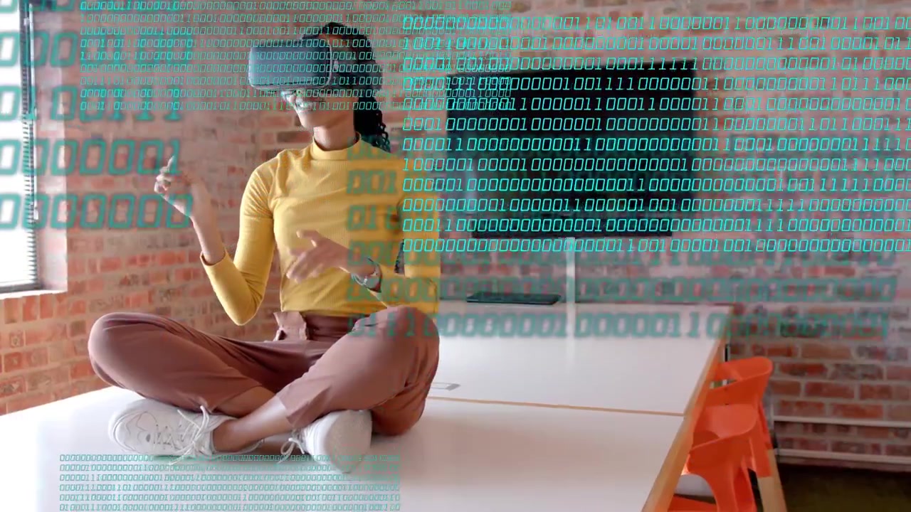 Woman sitting cross-legged on table, raising right finger and manipulating VR headset HUD for demo