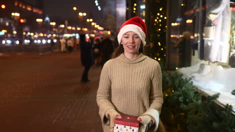 woman with a gift on a city street at night