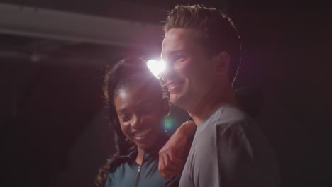 studio portrait of smiling athletic couple or friends in fitness clothing training shot in gym with low key lighting 2